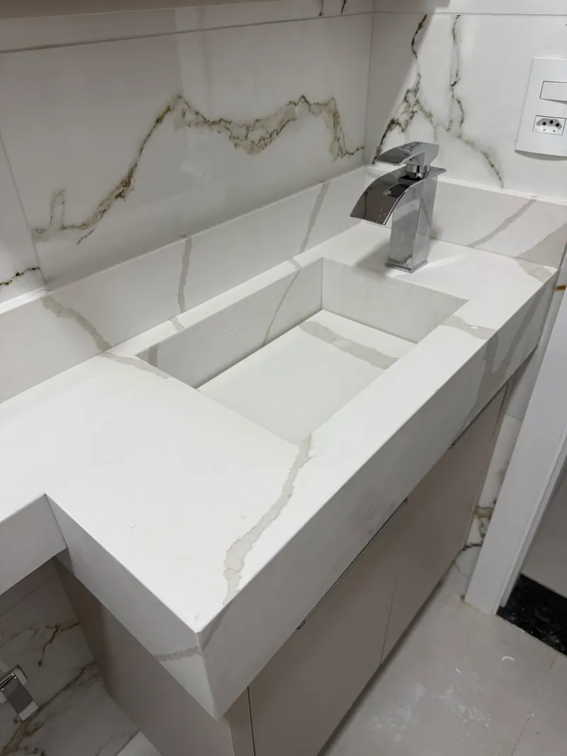 Detalhe de cuba esculpida e bancada clara com veios, em lavabo realizado pela marmoraria