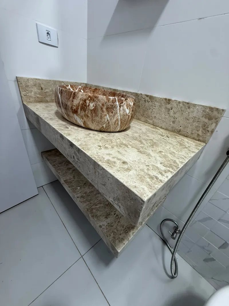Bancada de lavabo em pedra clara com cuba de apoio de tons naturais