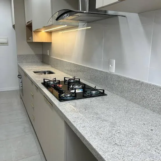 Bancada de cozinha em pedra cinza com cooktop e armários claros